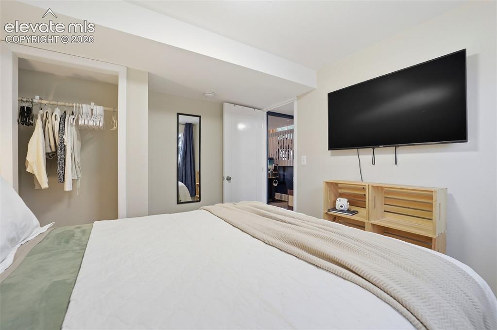 Image 19 of 38: Bedroom featuring an open closet with hanging rod, a wall-mounted mirror, a