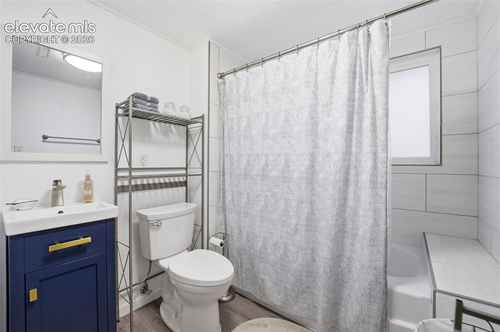 Image 20 of 38: Bathroom featuring a blue vanity with gold hardware, a white sink, and a fr