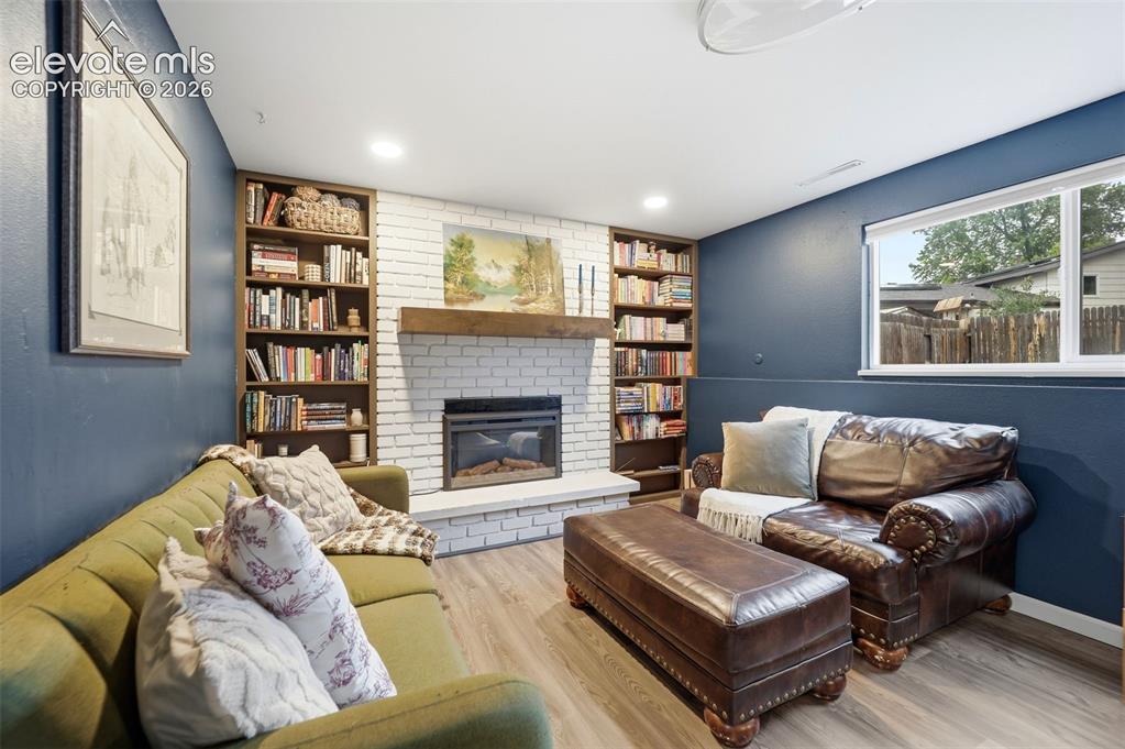 Image 22 of 38: Living area featuring a white brick fireplace with a wood mantle, built-in