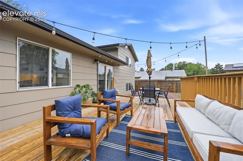 Image 36 of 38: Expansive outdoor wood deck featuring string lighting, wood railing, and di