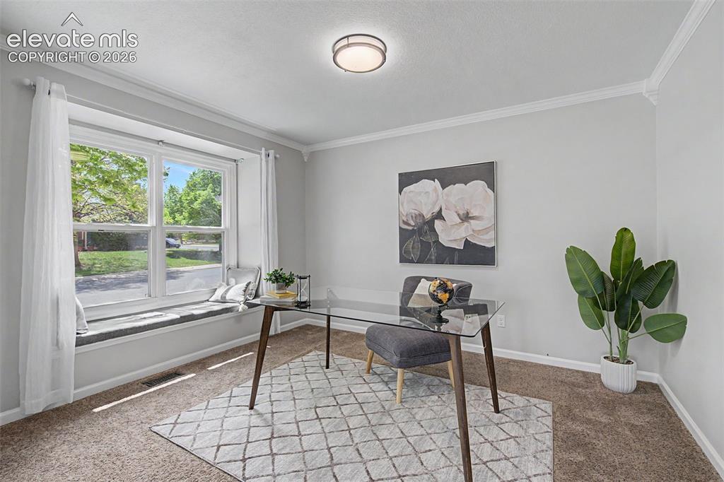 Image 25 of 47: Office space at the front of the home with window seat and crown molding