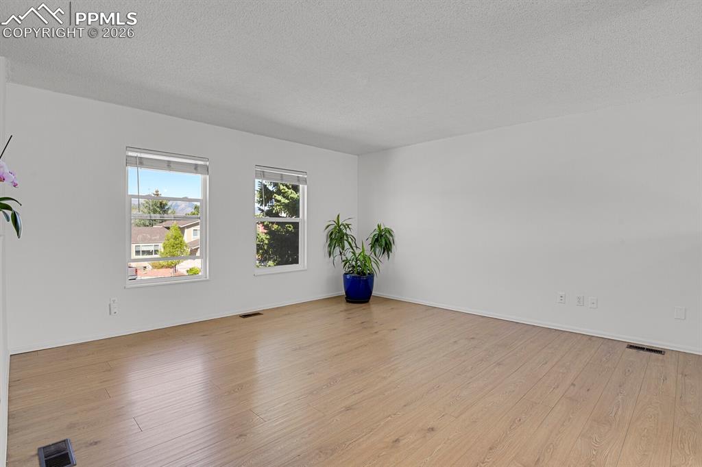 Image 12 of 30: Bright room featuring two windows, light  floors, and white walls