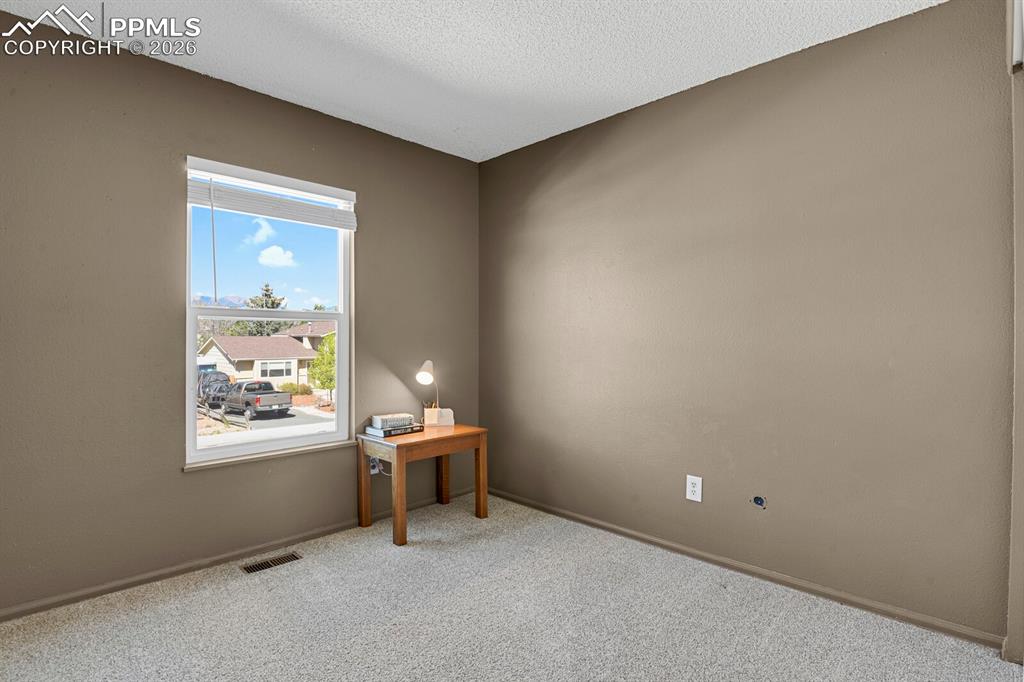 Image 14 of 30: This room features light-colored carpeting, neutral painted walls, and a wi