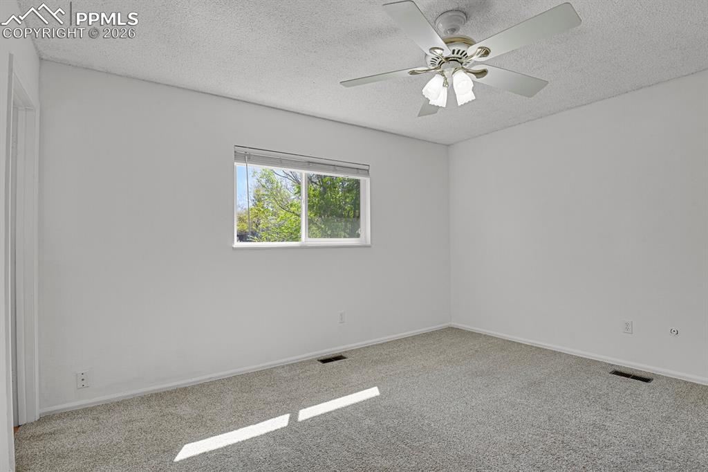 Image 18 of 30: Spacious room featuring carpeting, a window offering views of greenery, and