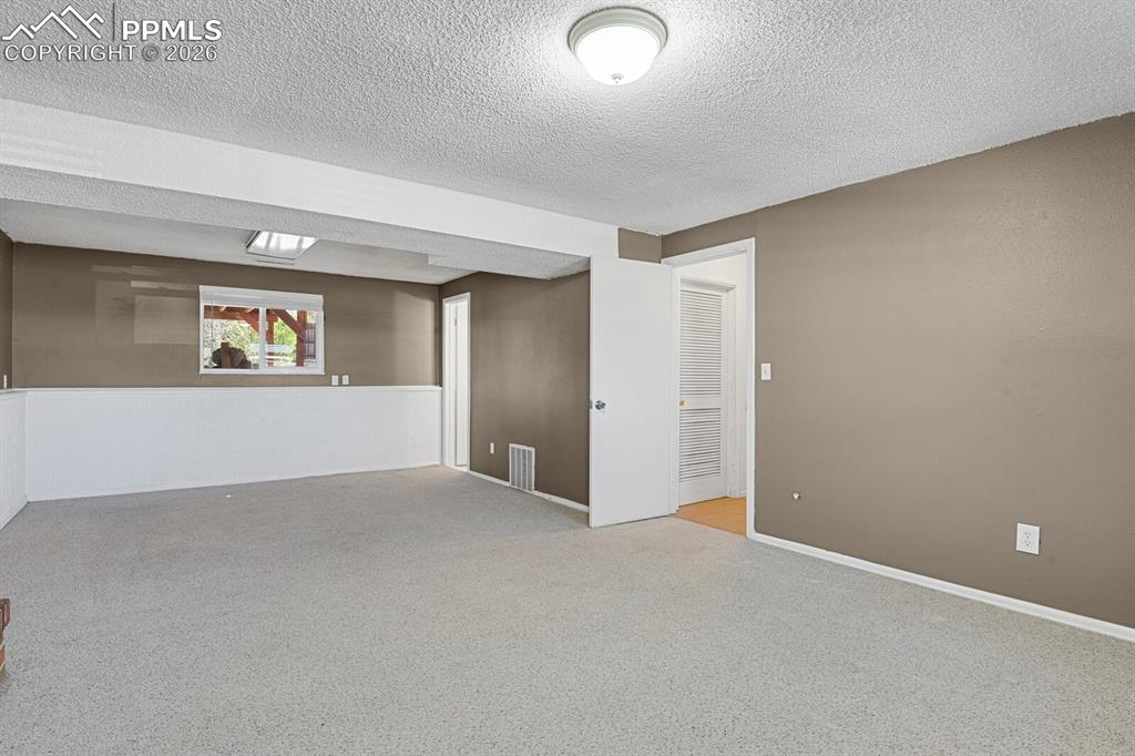 Image 20 of 30: The room features light-colored carpeting, neutral-toned walls, and a windo