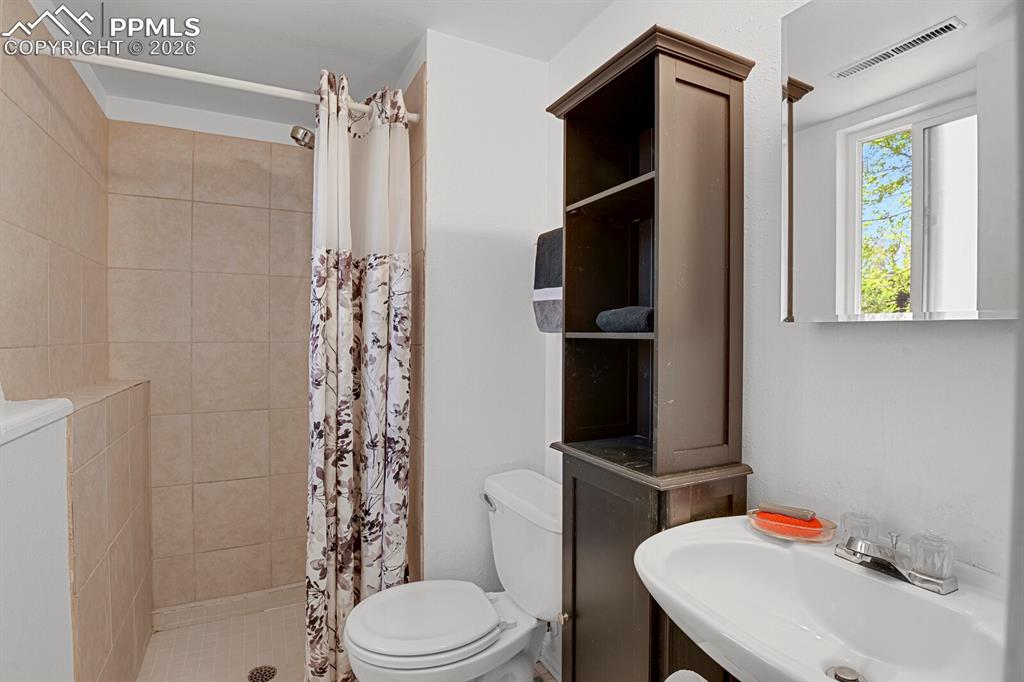 Image 22 of 30: This lower level bathroom features a shower with tiled walls and a shower c