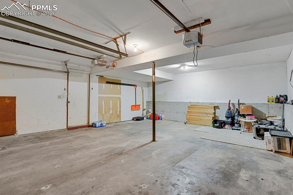 Image 23 of 30: Spacious garage with concrete flooring, white painted walls, and overhead l