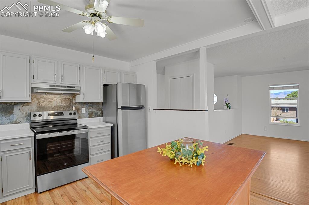 Image 7 of 30: The kitchen features light-colored cabinetry, stainless steel appliances, a