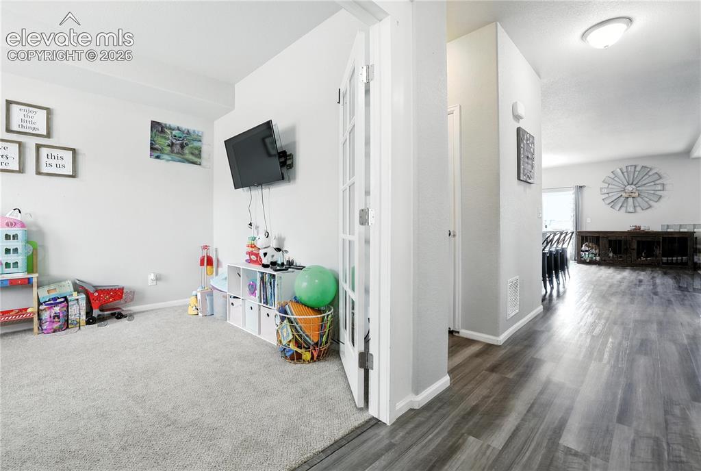 Image 12 of 42: Neutral-toned carpeting, wood-finish flooring, and a semi-flush ceiling lig