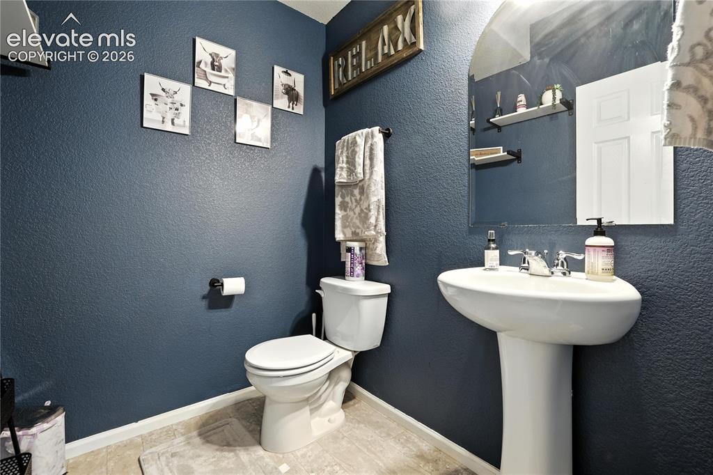 Image 15 of 42: Pedestal sink with chrome fixtures, an arched mirror, and wall-mounted shel