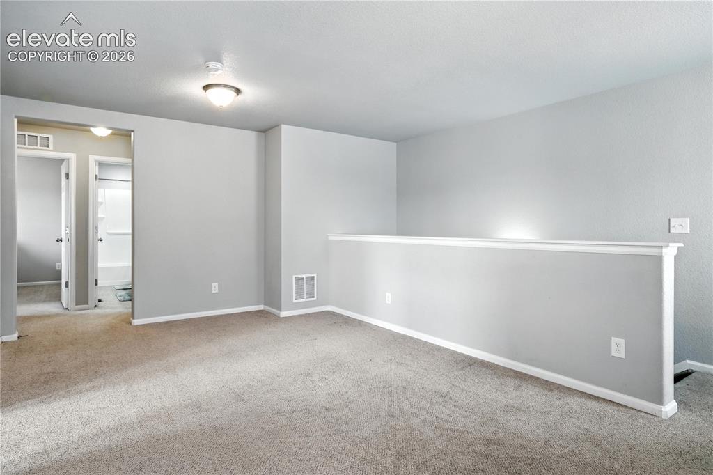 Image 17 of 42: Carpeted loft area with light gray walls, white trim, and a flush mount cei