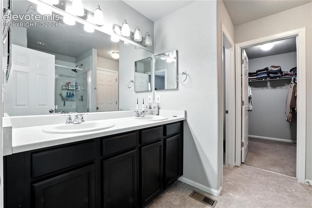 Image 22 of 42: Double vanity with white countertops, dark wood-finish cabinetry, and polis