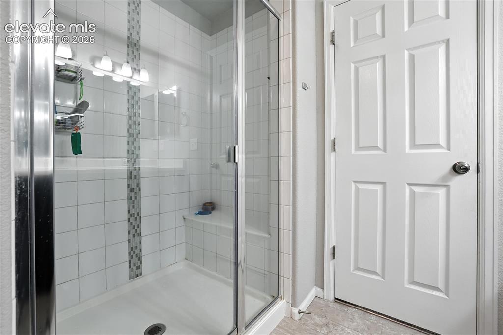 Image 23 of 42: Glass-enclosed shower with a built-in bench, white tile surround, and decor