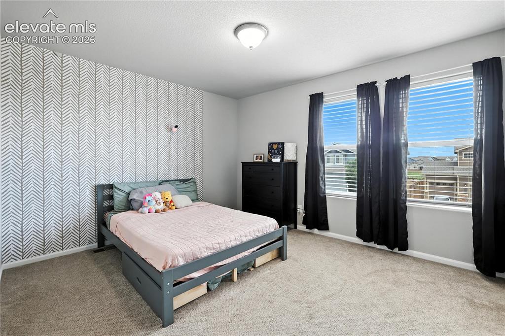 Image 25 of 42: Accent wall with geometric wallpaper, wall-to-wall carpeting, and three win