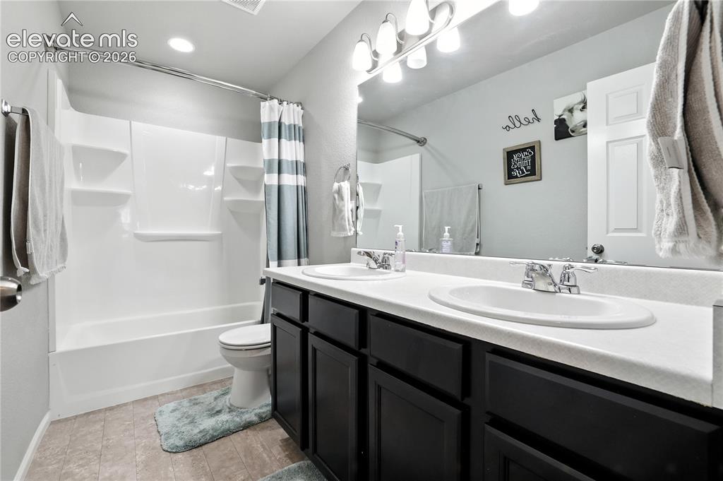 Image 29 of 42: Double vanity with integrated sinks, dark wood-finish cabinetry, and an exp