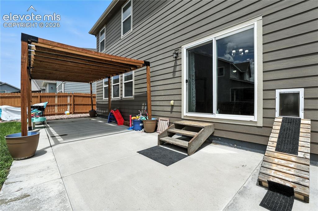 Image 33 of 42: Concrete patio featuring a wood pergola, vinyl siding, sliding glass door, 