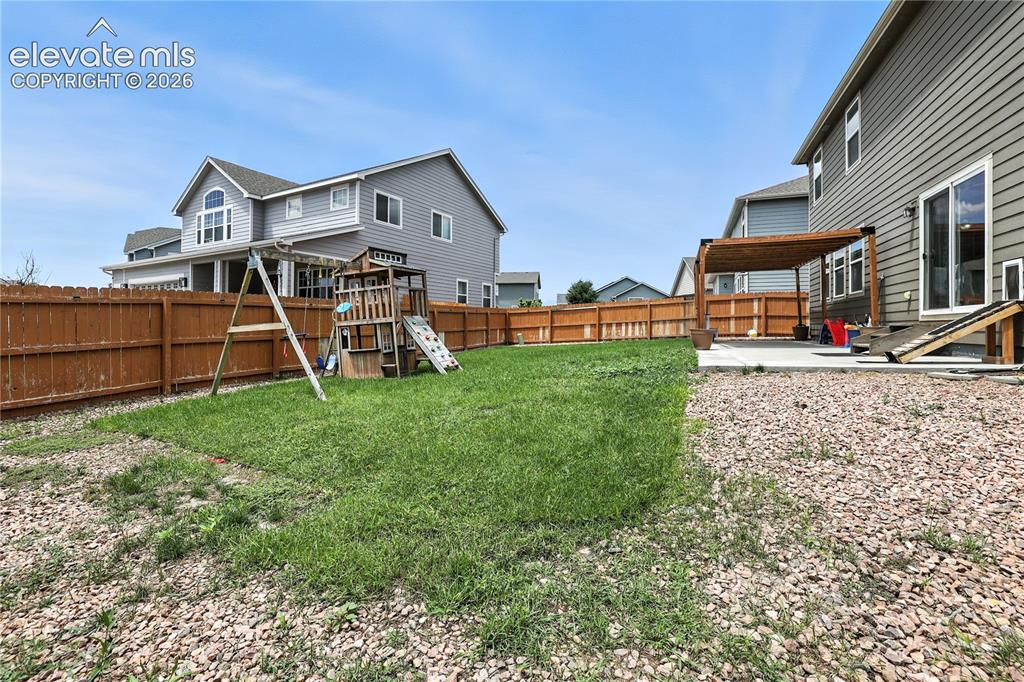 Image 37 of 42: Expansive backyard featuring a concrete patio with a wooden pergola, a larg