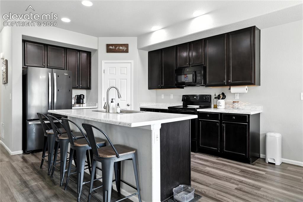 Image 5 of 42: Kitchen featuring dark wood-finish cabinetry, light countertops, wood-finis