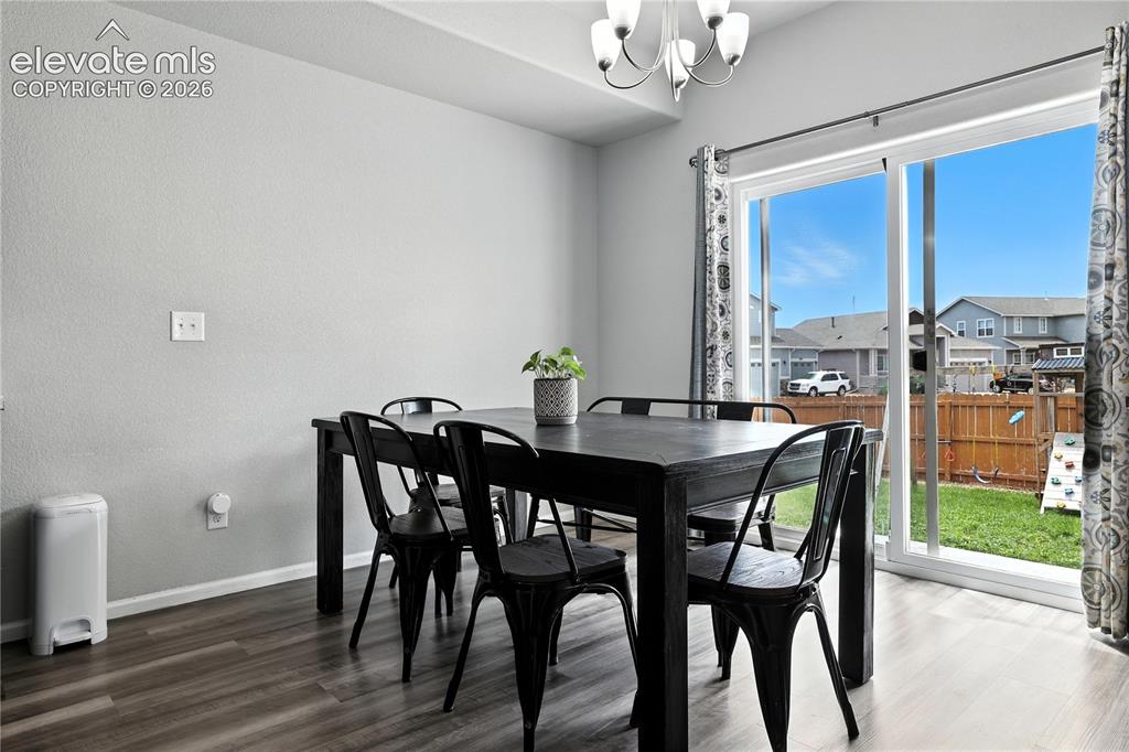 Image 7 of 42: Sliding glass door, wood-finish flooring, overhead chandelier, light-toned 