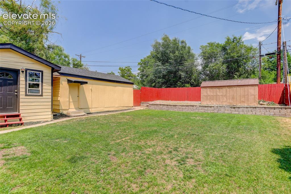 Image 13 of 18: Fully fenced yard w/ storage sheds
