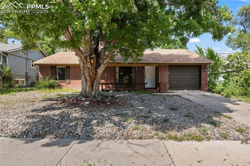 Caption: Single story home featuring a shingled roof, brick siding, concrete driveway, and an attached garage