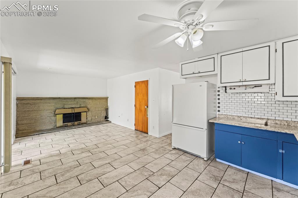 Image 20 of 27: Kitchen with backsplash, freestanding refrigerator, a fireplace, blue cabin