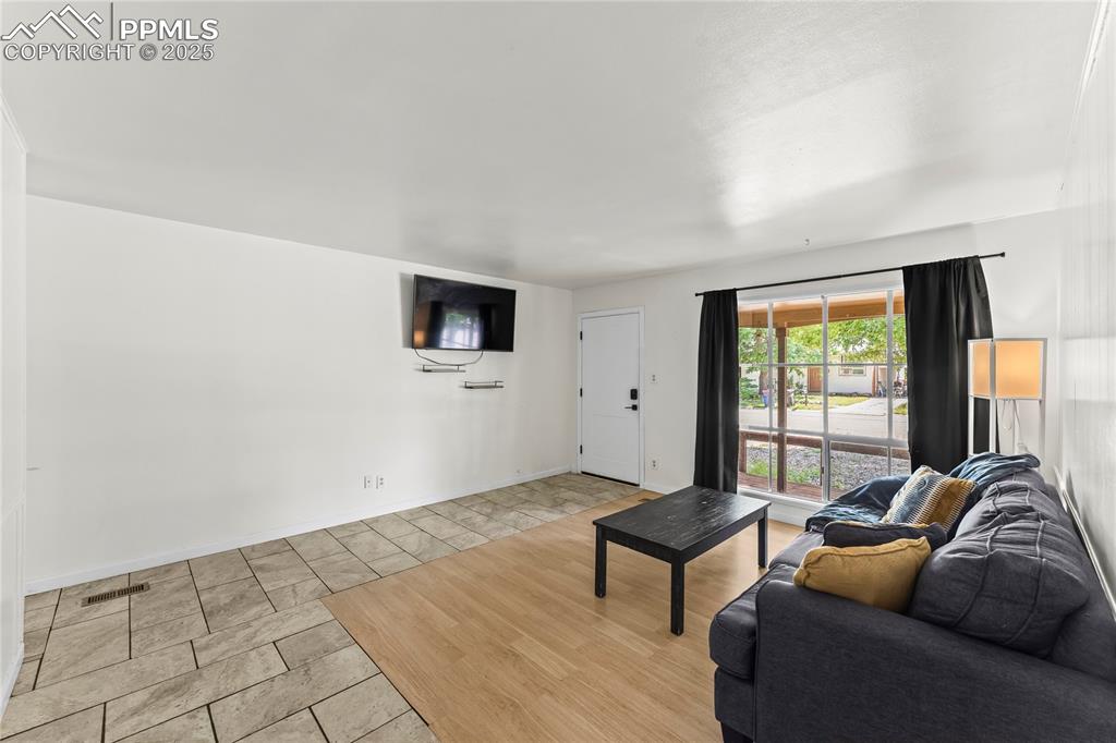 Image 5 of 27: Living room with light tile patterned flooring and baseboards