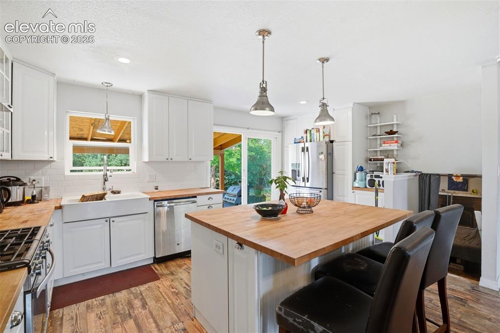 Image 10 of 34: White cabinetry, wood-finish countertops, stainless steel appliances, a far