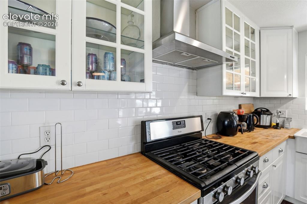 Image 11 of 34: White subway tile backsplash, natural wood countertops, stainless steel gas