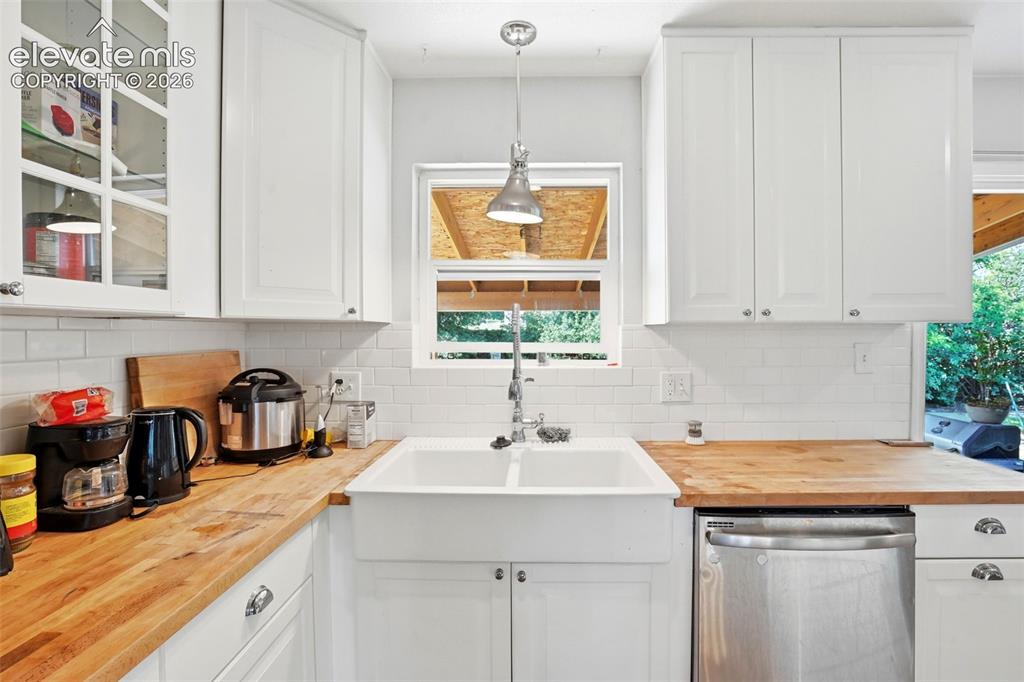 Image 12 of 34: White upper cabinetry with glass-front accents, butcher block countertops, 