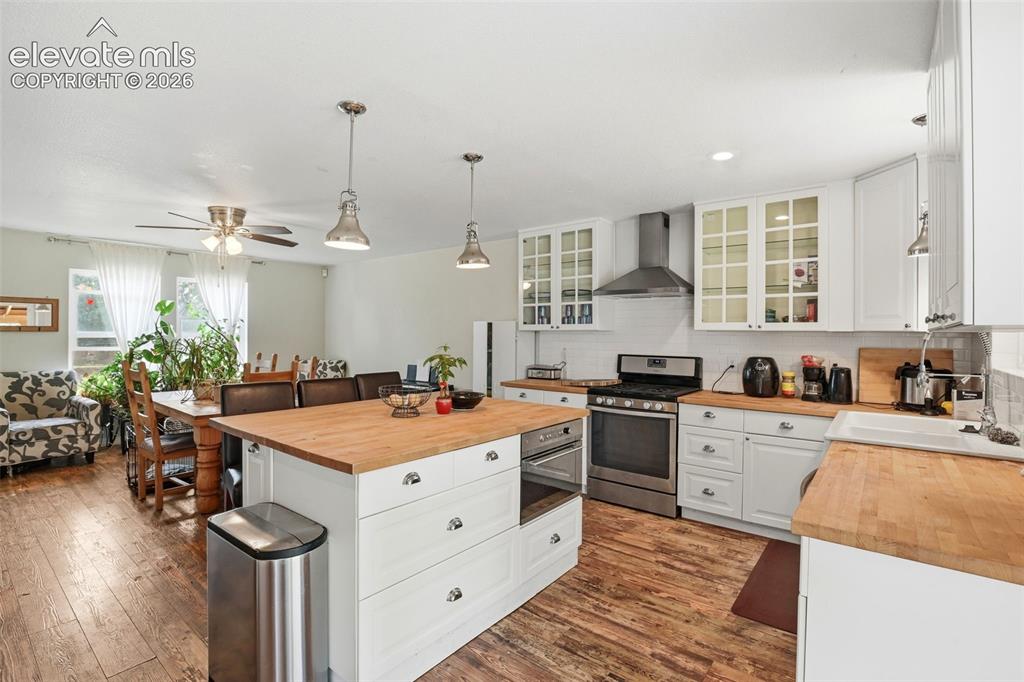 Image 14 of 34: Kitchen featuring white cabinetry, butcher block countertops, stainless ste