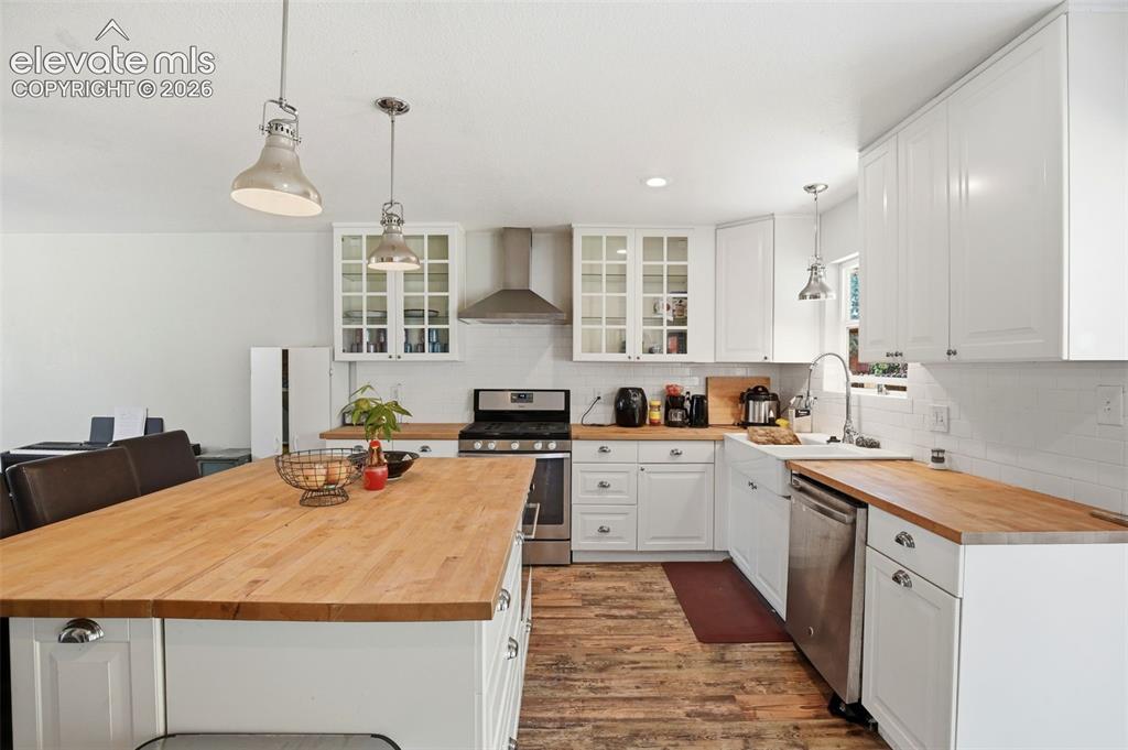 Image 15 of 34: Kitchen featuring white cabinetry, butcher block countertops, stainless ste