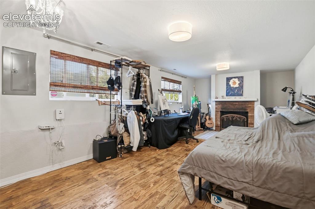 Image 16 of 34: Wood-finish flooring, white walls, and a brick fireplace with a white mante