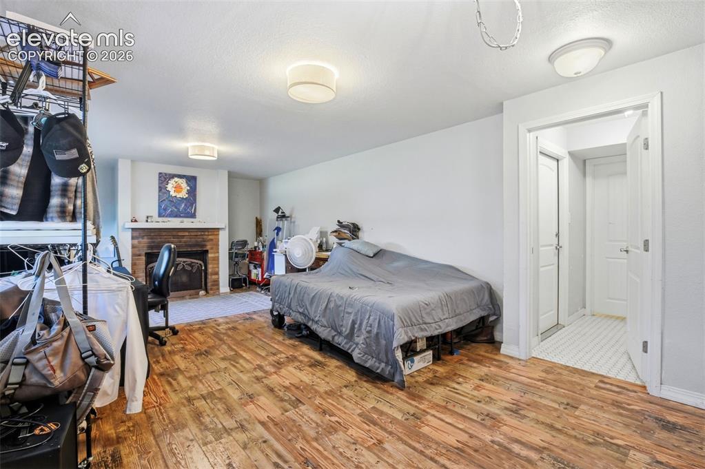 Image 17 of 34: Wood-finish flooring, brick fireplace with wood mantel, flush-mount lightin
