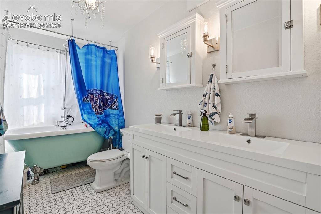 Image 20 of 34: Dual vanity with chrome faucets, white cabinetry, and recessed medicine cab