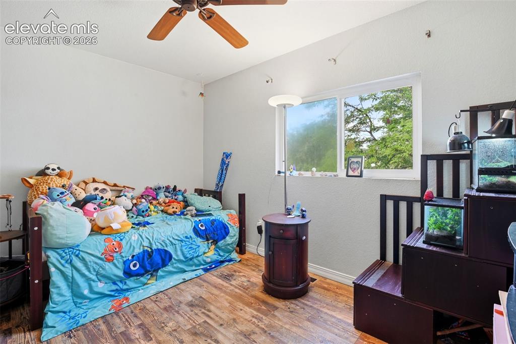 Image 21 of 34: Wood-finish flooring, white walls, and a ceiling fan with integrated lighti