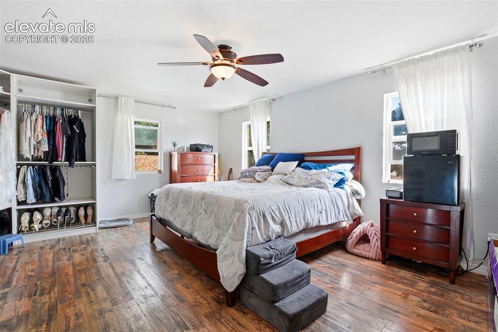 Image 27 of 34: Wood-finish flooring, ceiling fan, and built-in closet shelving