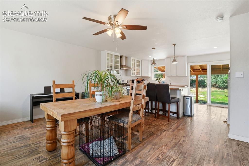 Image 5 of 34: Wood-finish flooring, white cabinetry, stainless steel appliances, pendant 