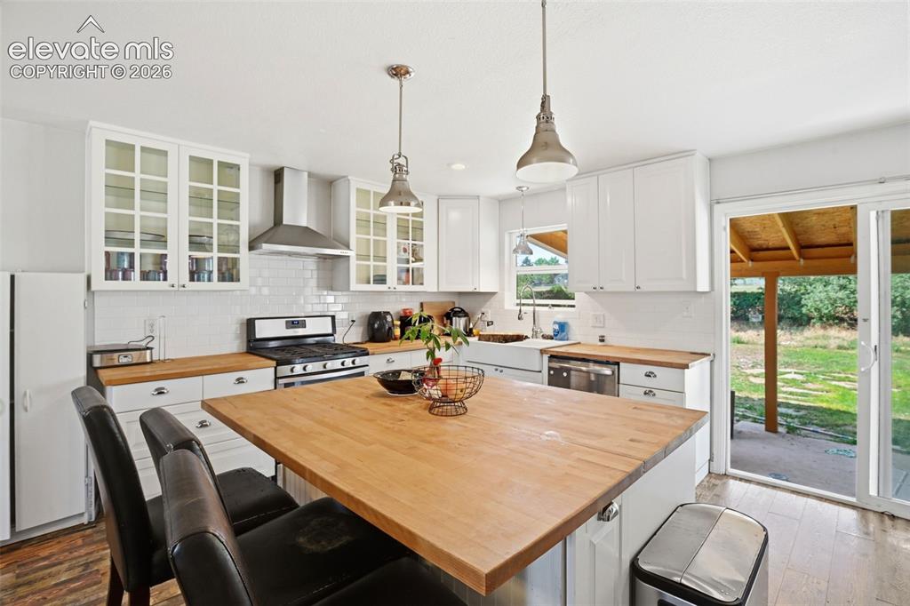 Image 9 of 34: Kitchen featuring white cabinetry, wood-finish countertops, stainless steel
