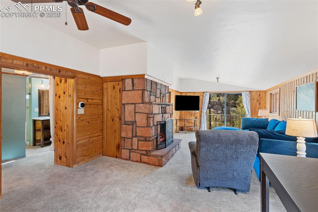 Image 16 of 35: upper level living room with vaulted ceiling, fireplace, and deck with view