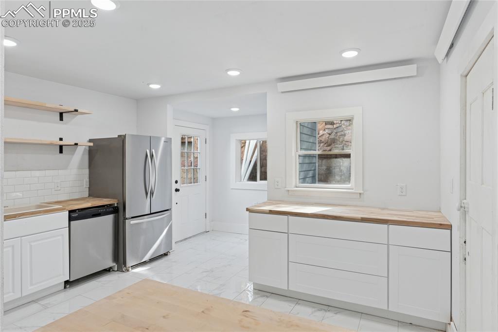 Image 15 of 45: Main-level flat kitchen with door to rear area of the property