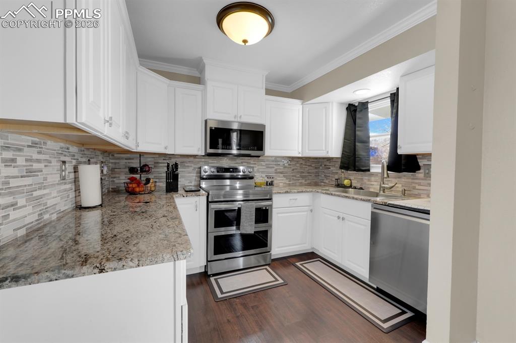 Image 3 of 29: Kitchen featuring stainless steel appliances, granite countertops and crown