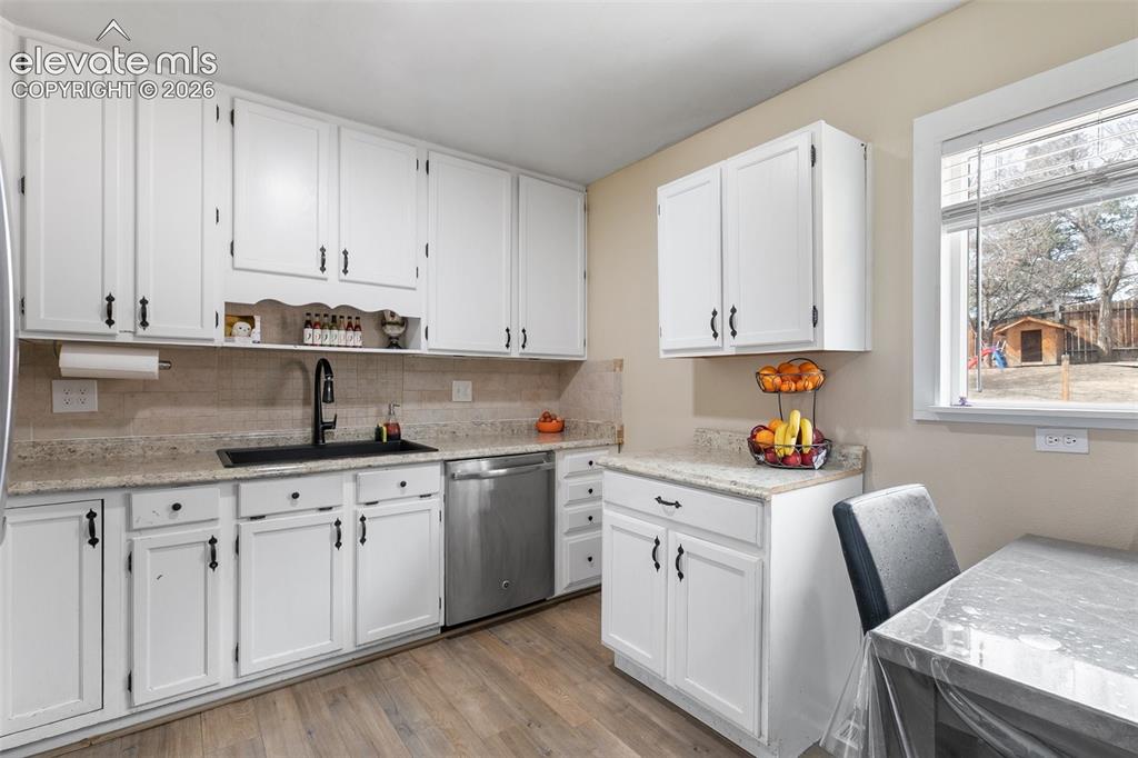 Image 10 of 29: Kitchen featuring white cabinetry, stone-finish countertops, a black basin