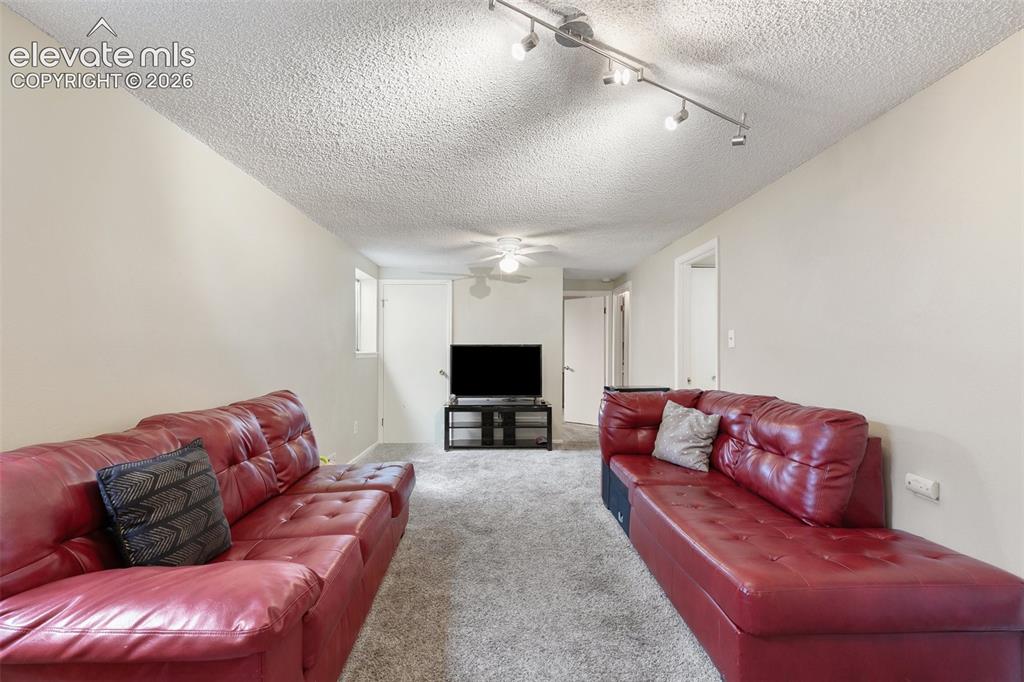 Image 19 of 29: Spacious living area featuring neutral-toned walls, textured ceiling, and t