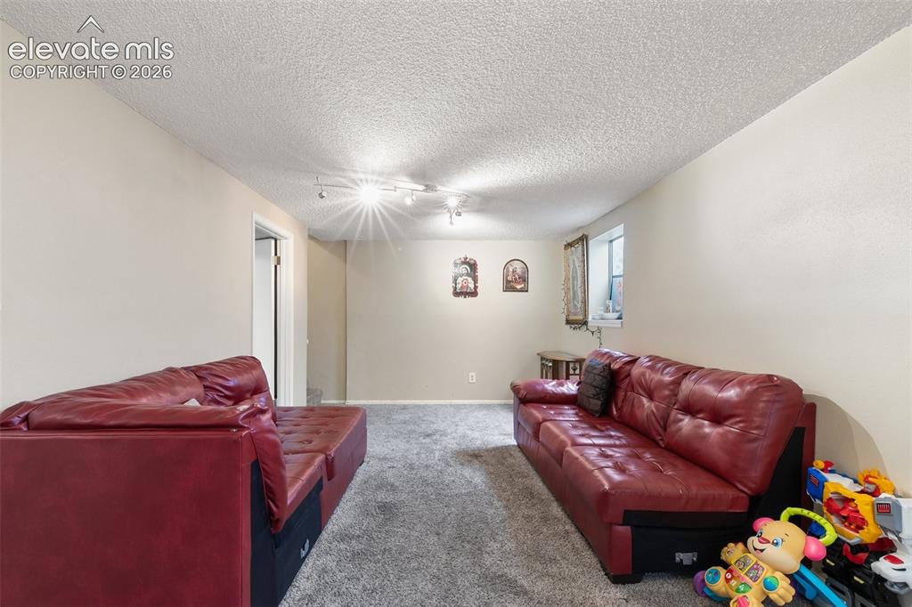 Image 21 of 29: Spacious room featuring neutral wall paint, textured ceiling, and track lig
