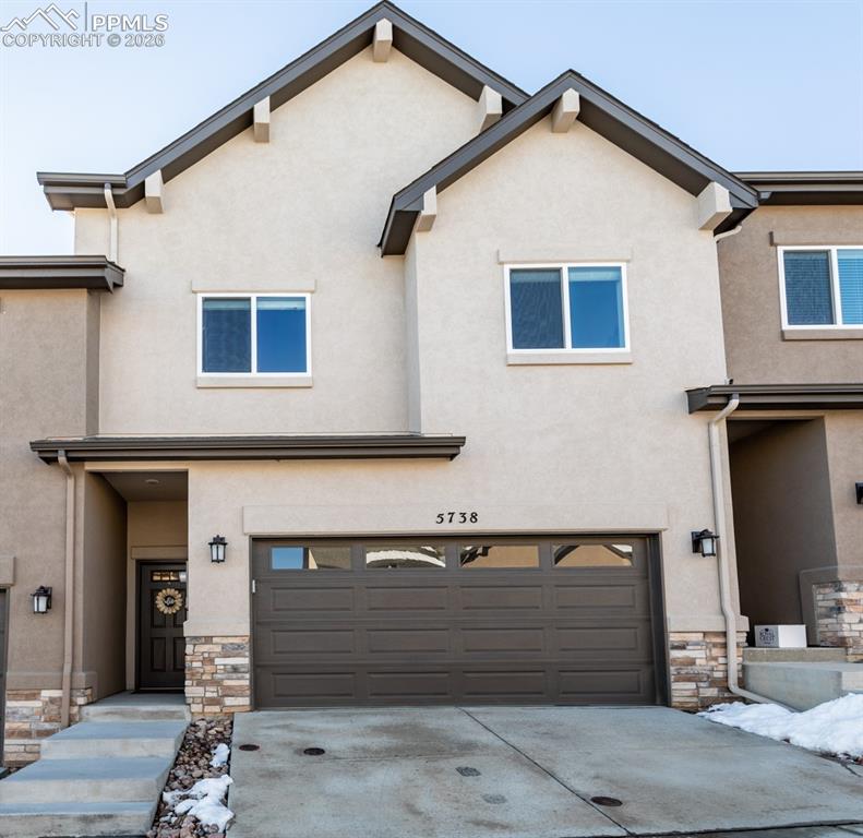 Caption: Traditional-style home featuring stone siding, a garage, stucco siding, and driveway