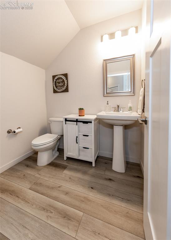 Image 10 of 49: Half bathroom with vaulted ceiling and light wood-type flooring