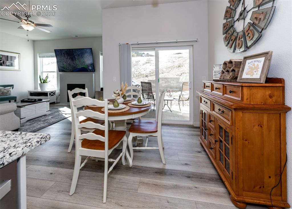 Image 17 of 49: Dining space featuring a ceiling fan, light wood-style floors, and a firepl