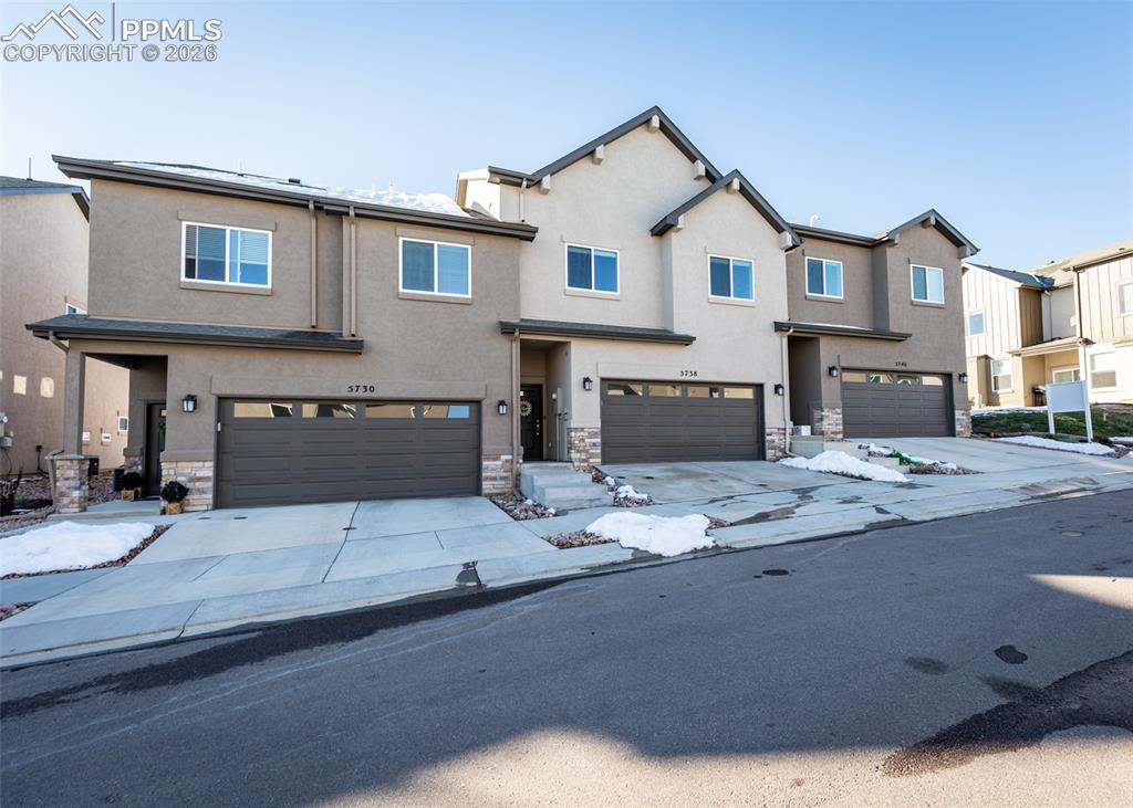Image 2 of 49: Traditional-style house featuring stone siding, an attached garage, stucco 