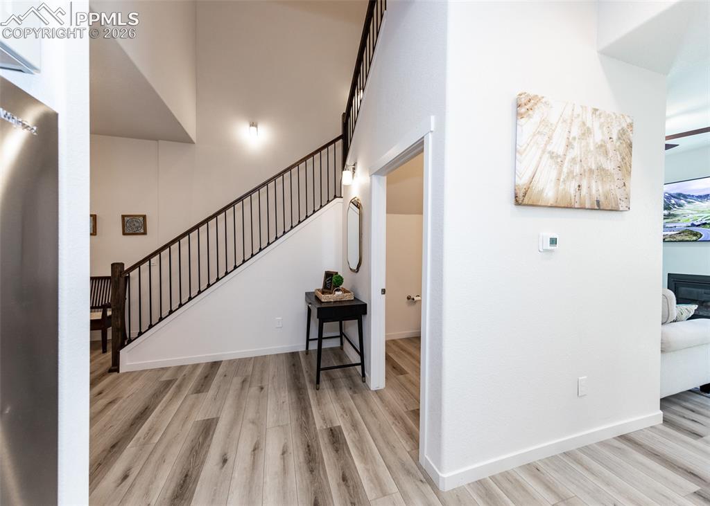 Image 8 of 49: Staircase with wood finished floors, a glass covered fireplace, and a high 